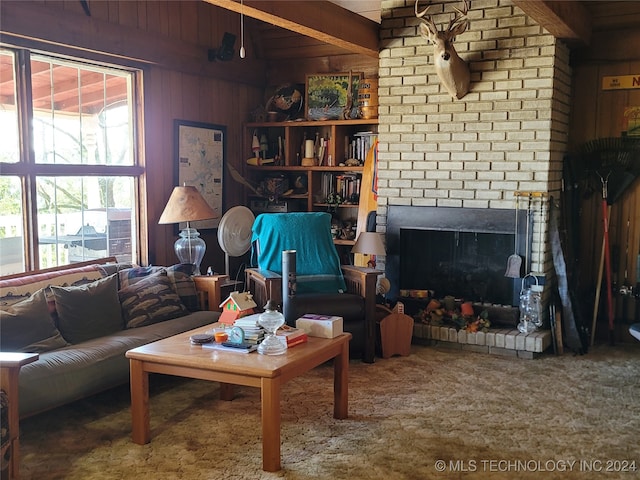 living room featuring a healthy amount of sunlight, wooden walls, beam ceiling, and a brick fireplace