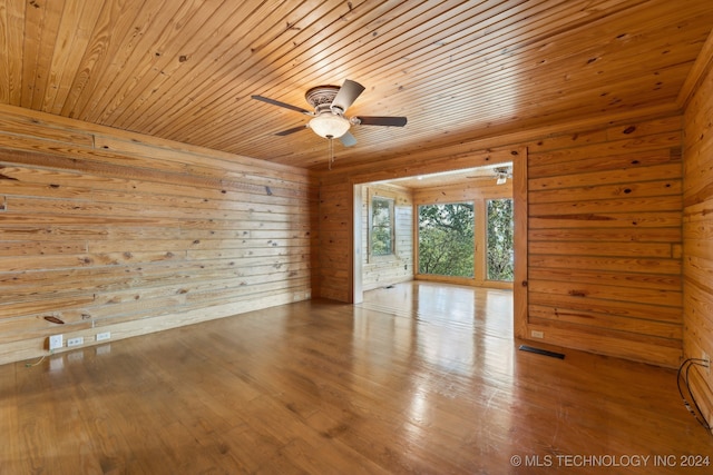 unfurnished room with wooden walls, ceiling fan, hardwood / wood-style floors, and wood ceiling