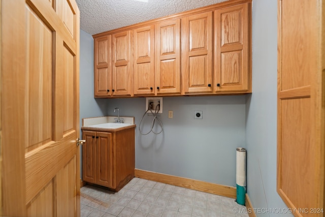 clothes washing area with sink, a textured ceiling, cabinets, hookup for a washing machine, and electric dryer hookup