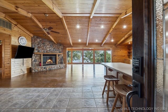 interior space featuring wood walls, wood ceiling, a stone fireplace, vaulted ceiling with beams, and hardwood / wood-style flooring