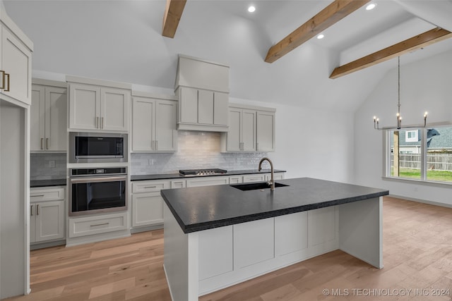 kitchen with beam ceiling, light hardwood / wood-style floors, appliances with stainless steel finishes, and a chandelier