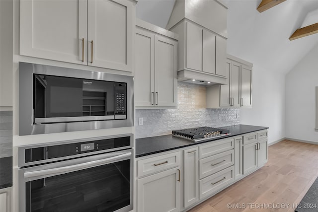 kitchen with vaulted ceiling with beams, light hardwood / wood-style flooring, backsplash, white cabinetry, and stainless steel appliances