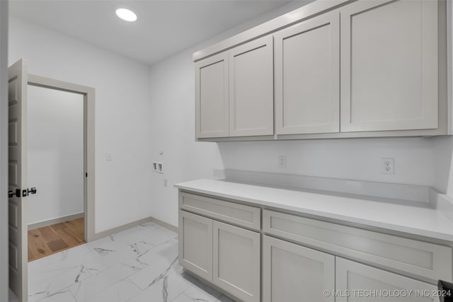 clothes washing area with light hardwood / wood-style flooring, washer hookup, and cabinets