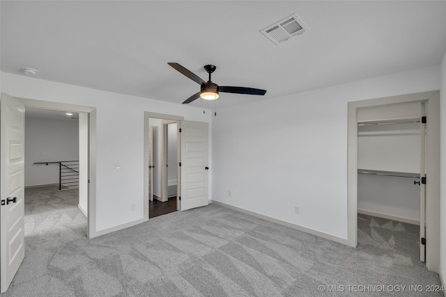 unfurnished bedroom featuring light carpet, ceiling fan, a walk in closet, and a closet