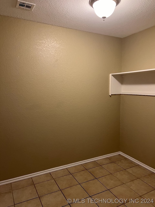 spare room with a textured ceiling and tile patterned flooring