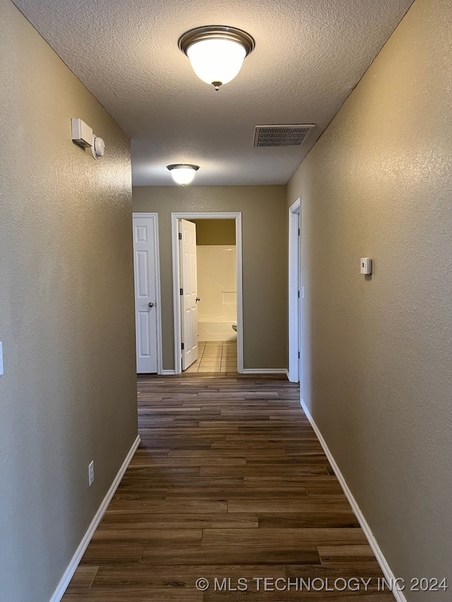 corridor featuring a textured ceiling and dark hardwood / wood-style floors