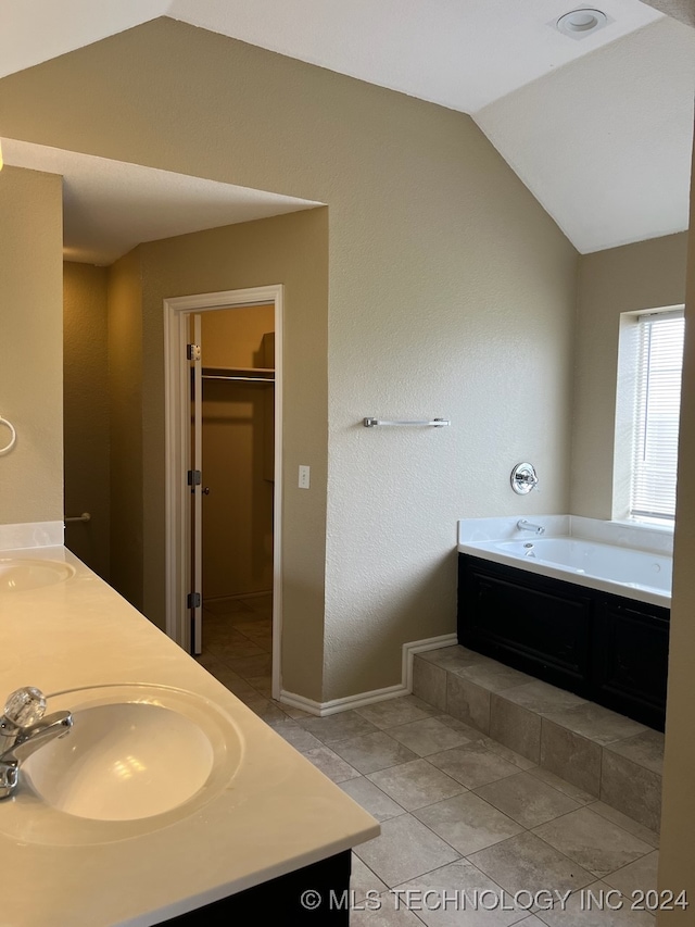 bathroom with lofted ceiling, tile patterned flooring, sink, and a tub to relax in