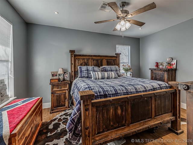 bedroom featuring multiple windows, hardwood / wood-style flooring, and ceiling fan