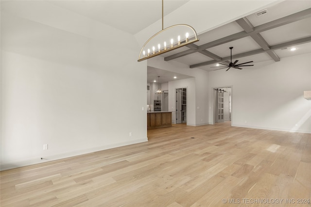 unfurnished living room featuring coffered ceiling, ceiling fan with notable chandelier, beamed ceiling, and light hardwood / wood-style flooring