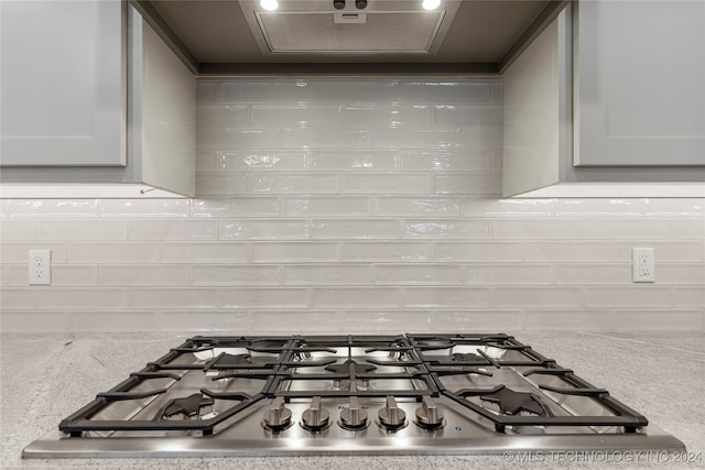 details with backsplash, stainless steel gas cooktop, and light stone counters