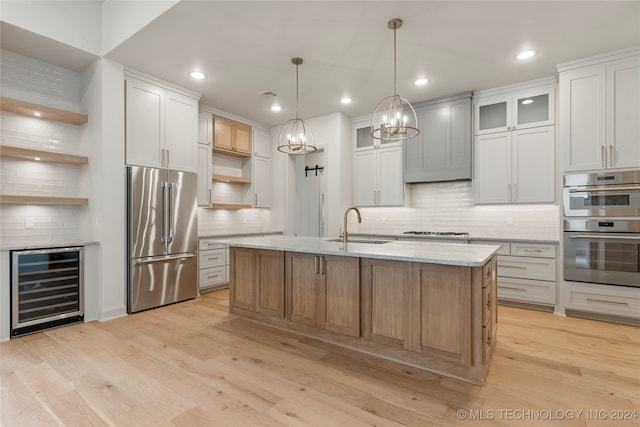 kitchen featuring stainless steel appliances, white cabinetry, beverage cooler, and a kitchen island with sink