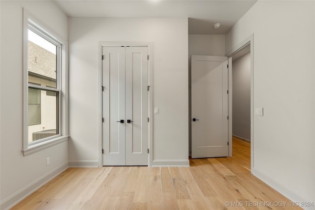 unfurnished bedroom with light hardwood / wood-style flooring and a closet