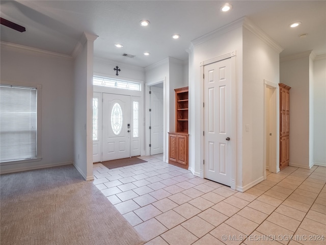 foyer with ceiling fan, light tile patterned floors, and crown molding