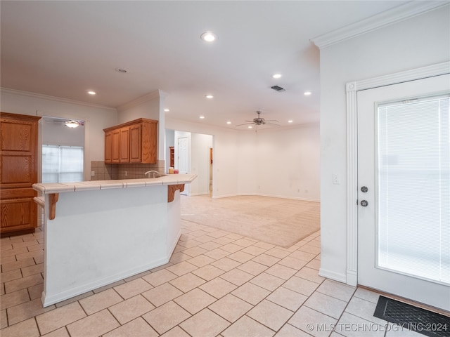 kitchen with ceiling fan, kitchen peninsula, a kitchen breakfast bar, tile counters, and light colored carpet