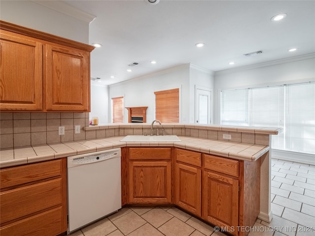 kitchen with sink, kitchen peninsula, tasteful backsplash, dishwasher, and tile counters