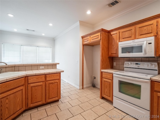 kitchen with sink, white appliances, backsplash, tile countertops, and crown molding