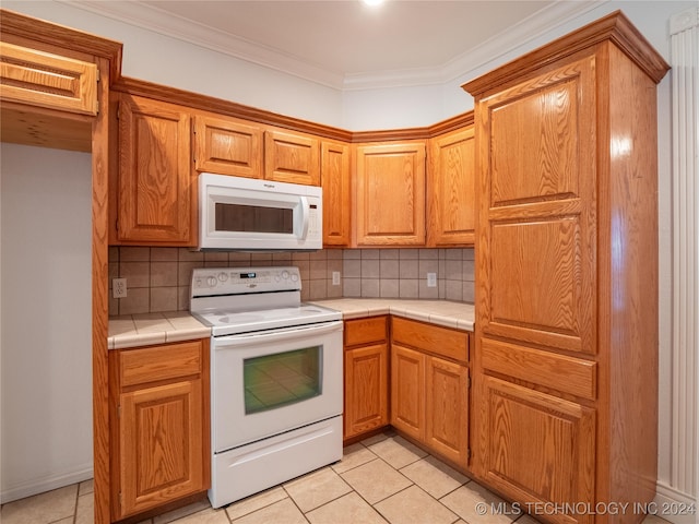 kitchen with crown molding, tile counters, white appliances, and tasteful backsplash