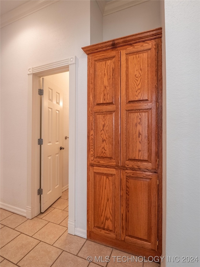 corridor featuring crown molding and light tile patterned floors