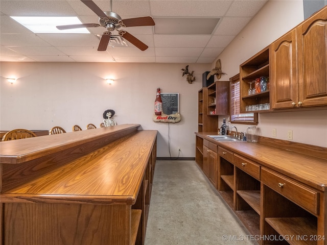 bar with butcher block counters, light colored carpet, ceiling fan, and sink