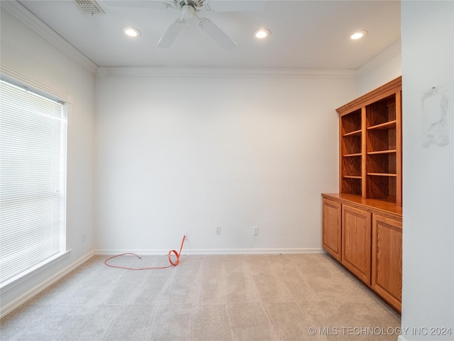 unfurnished room featuring ceiling fan, light carpet, ornamental molding, and a healthy amount of sunlight