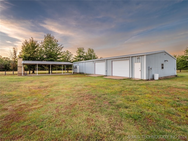 yard at dusk featuring a garage and an outbuilding