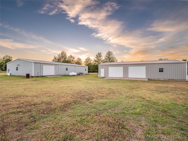 yard at dusk featuring an outbuilding and a garage