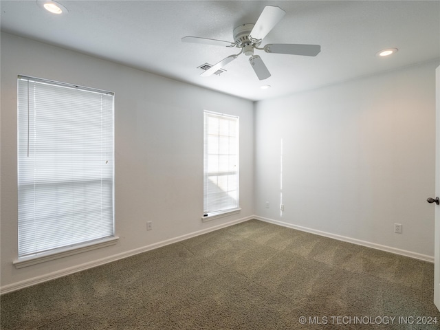 empty room featuring ceiling fan and dark colored carpet