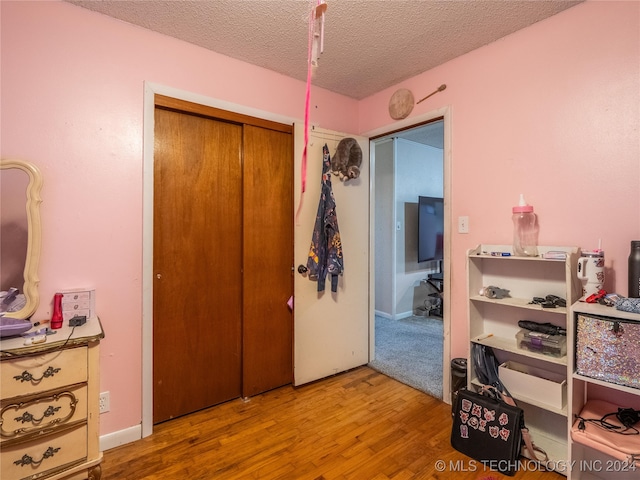 bedroom featuring light hardwood / wood-style flooring, a closet, and a textured ceiling