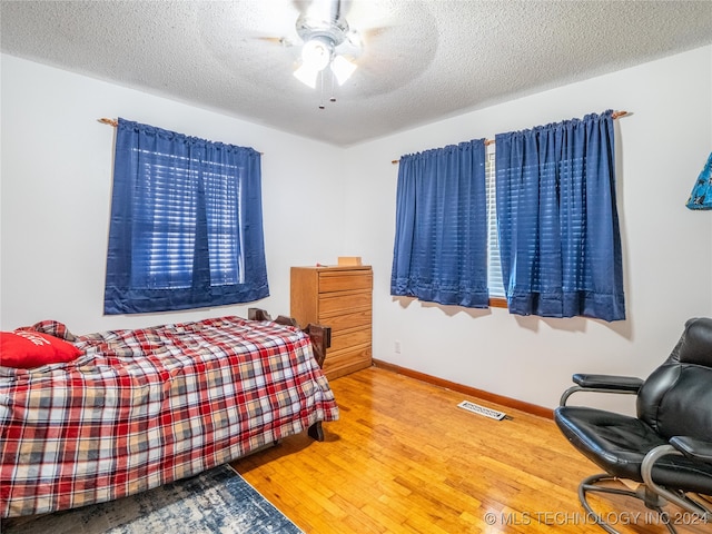 bedroom featuring a textured ceiling, wood-type flooring, and ceiling fan