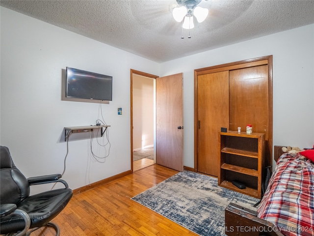 bedroom with light hardwood / wood-style flooring, a closet, ceiling fan, and a textured ceiling