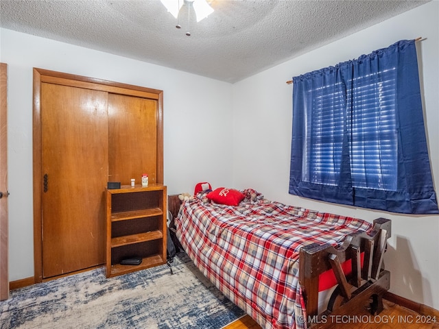 bedroom with a textured ceiling, ceiling fan, and a closet