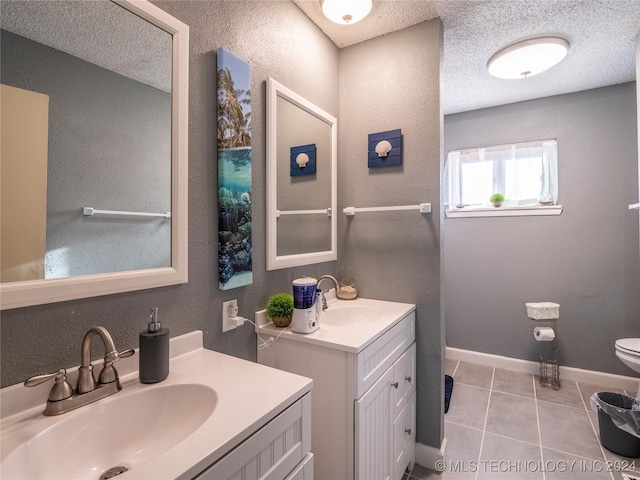 bathroom with a textured ceiling, tile patterned flooring, vanity, and toilet