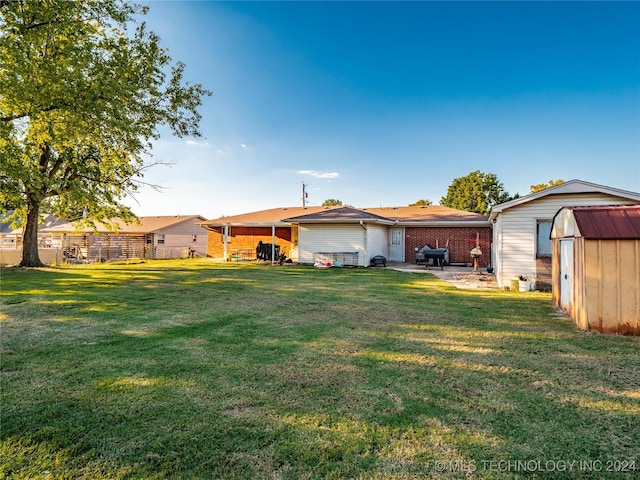 rear view of property featuring a lawn, a patio, and a shed