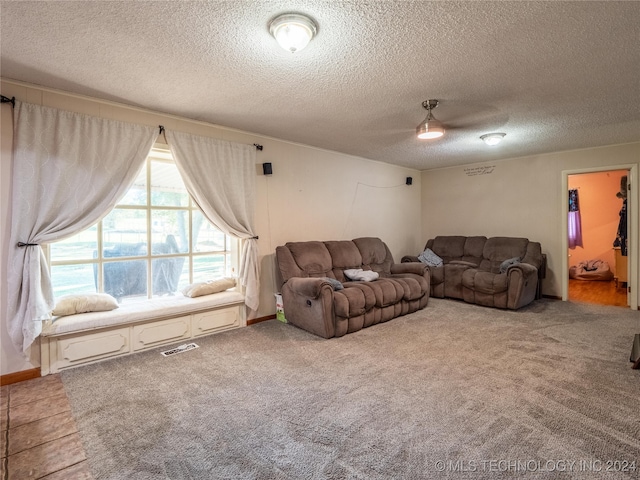 living room featuring carpet, ceiling fan, and a textured ceiling