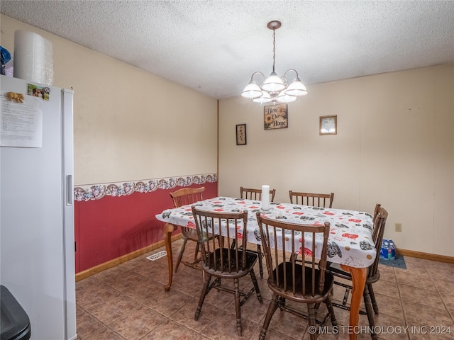 dining area featuring an inviting chandelier and a textured ceiling