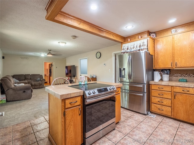 kitchen with ceiling fan, backsplash, appliances with stainless steel finishes, tile countertops, and light carpet