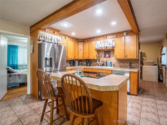 kitchen with sink, a kitchen island, appliances with stainless steel finishes, a kitchen bar, and decorative backsplash