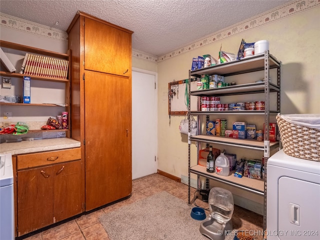 interior space featuring cabinets, light tile patterned floors, a textured ceiling, and washer / dryer