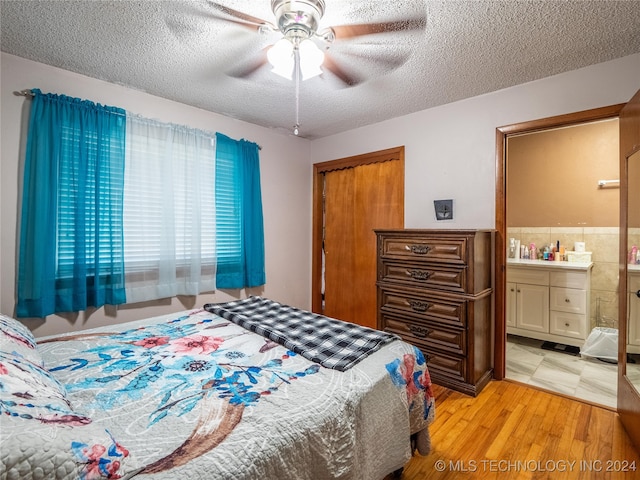 bedroom with a closet, a textured ceiling, light hardwood / wood-style flooring, ensuite bathroom, and ceiling fan