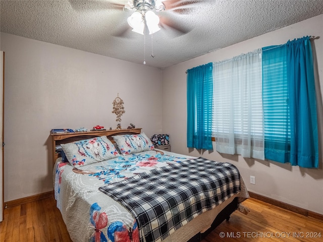 bedroom with wood-type flooring, ceiling fan, and a textured ceiling