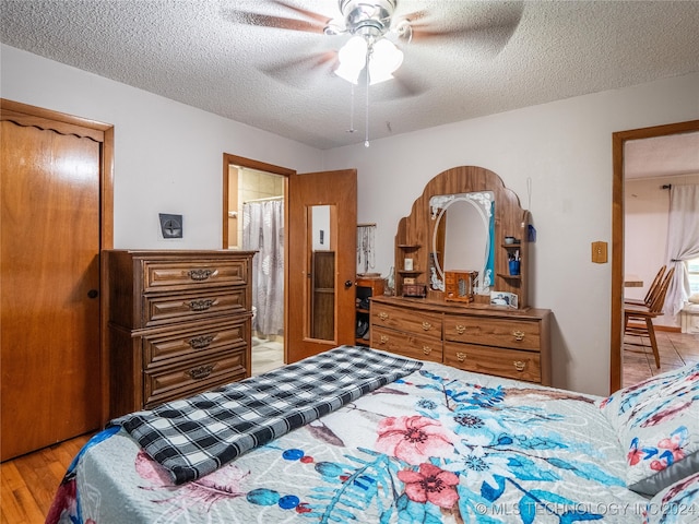 bedroom featuring light hardwood / wood-style floors, ceiling fan, ensuite bathroom, and a textured ceiling