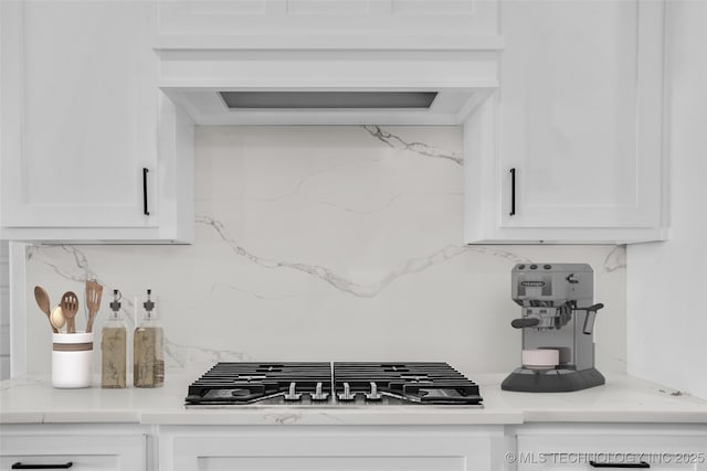 kitchen with light stone counters, white cabinets, decorative backsplash, and stainless steel gas stovetop