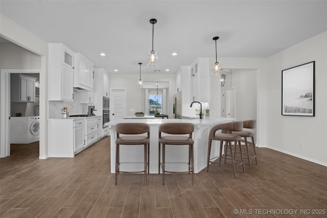 kitchen featuring hanging light fixtures, washer / dryer, stainless steel appliances, and white cabinets