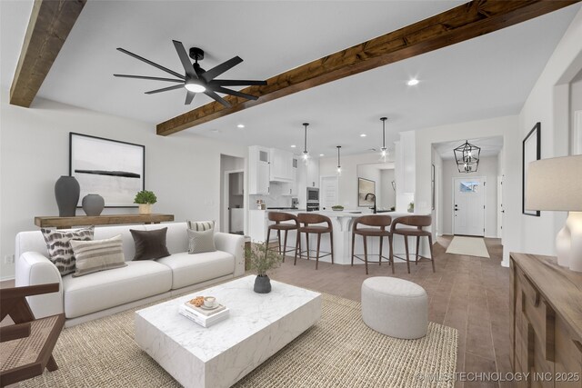 living room featuring beamed ceiling, sink, ceiling fan with notable chandelier, and light hardwood / wood-style floors