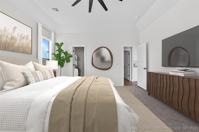 carpeted bedroom with vaulted ceiling, a spacious closet, and ceiling fan