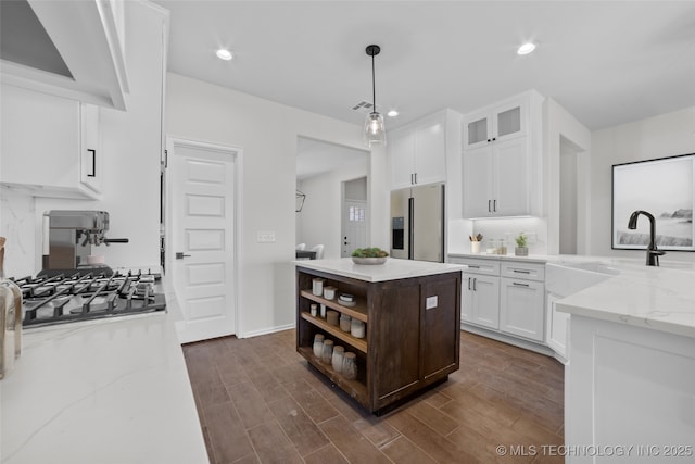 kitchen featuring pendant lighting, white cabinetry, sink, stainless steel appliances, and light stone countertops