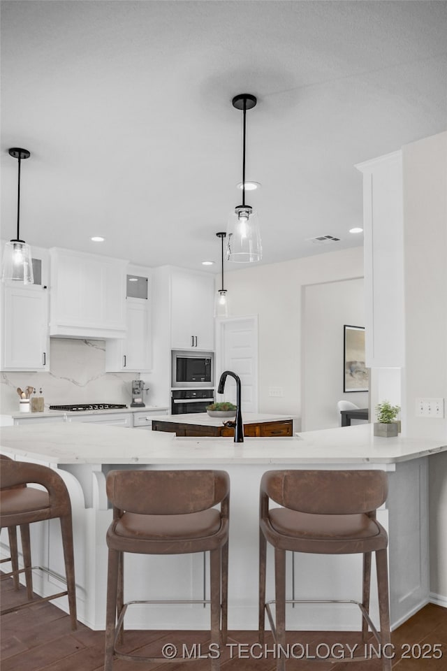 kitchen featuring built in microwave, white cabinetry, hanging light fixtures, and backsplash