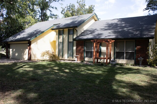 rear view of house featuring a yard and a garage