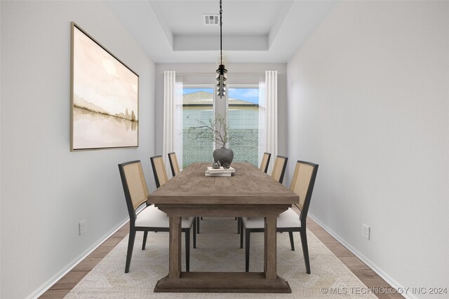 dining area with hardwood / wood-style floors and a tray ceiling