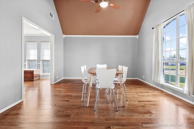 unfurnished dining area featuring ornamental molding, wood-type flooring, ceiling fan, and high vaulted ceiling